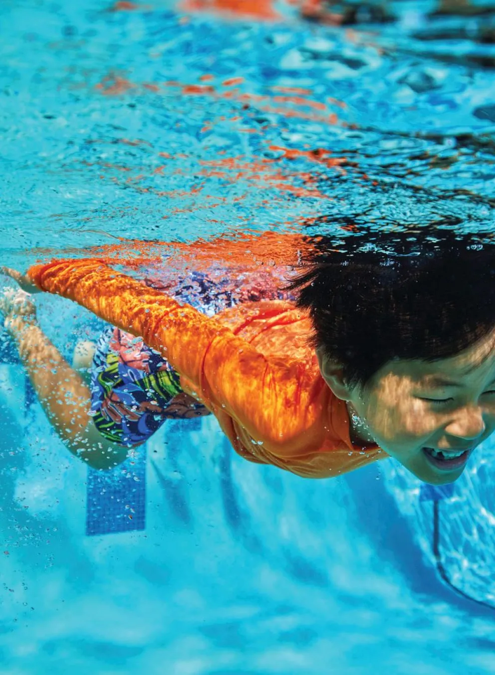 Young swimmer confidently swimming with an overhand stroke at the Kansas City YMCA pool.
