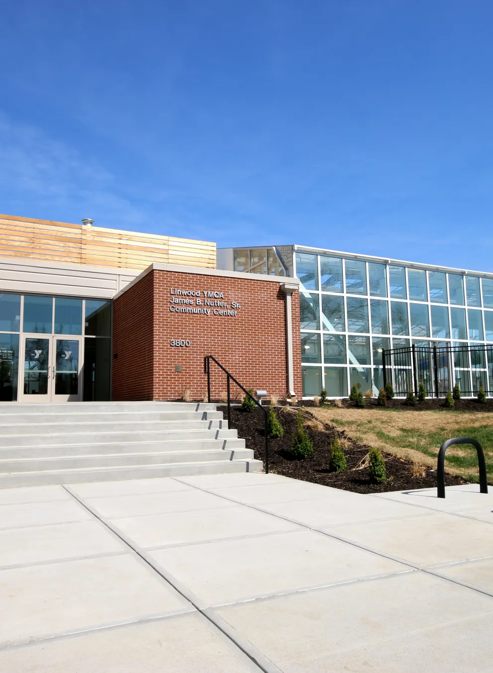 Exterior photo of Linwood YMCA/James B. Nutter, Sr. Community Center. Features Y Logo on the left side of the entrance with the building name on the right, even further to the right is floor to ceiling glass walls.