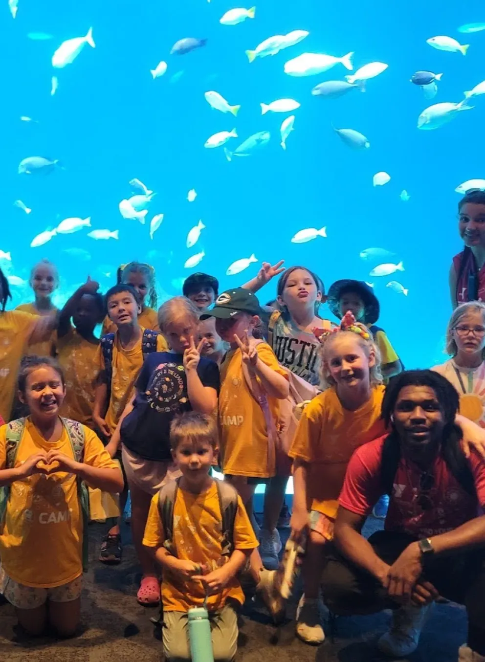 Photo of group of campers and staff on aquarium field trip with fish in the background