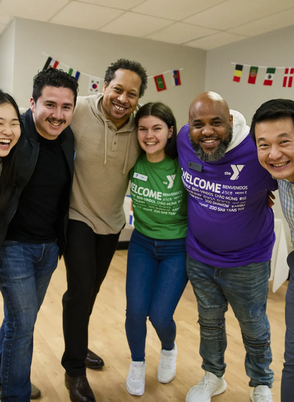 Picture of a diverse group of people joined in semi-circle, and smiling.
