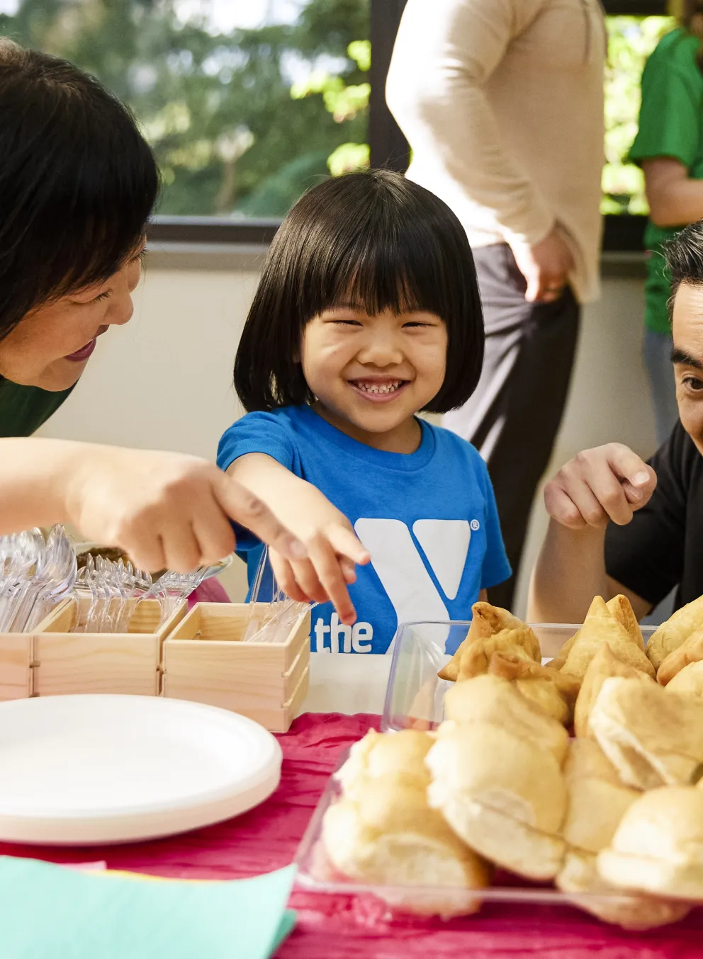 Family including young child shares food from around the world at welcoming week event