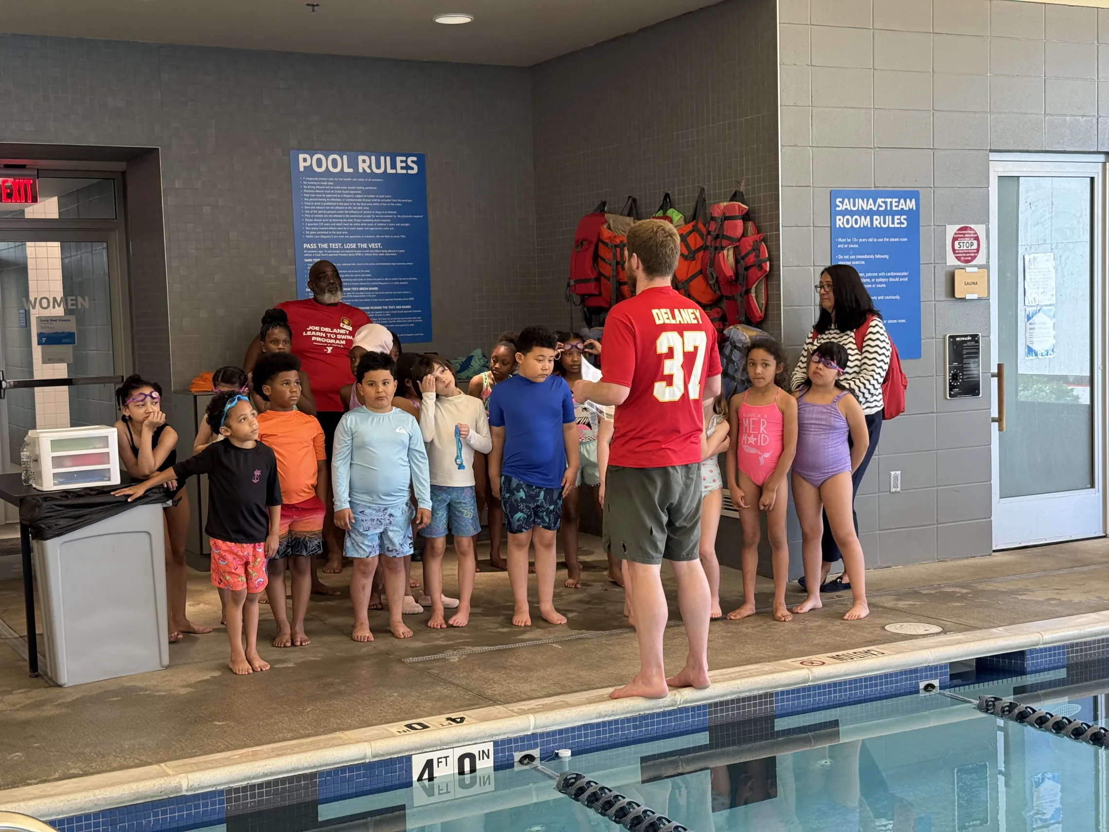 Picture of a group of student listening to a lifeguard before their water safety class.