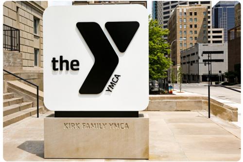 Photo of monument sign outside the Kirk Family YMCA. Include black logo on white background, with Kirk Family YMCA engraved on stone base