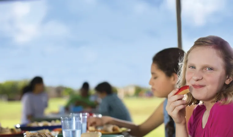 Young girl eating an apply slice in promotion of of the Nutrition Programs at the YMCA of Greater Kansas City