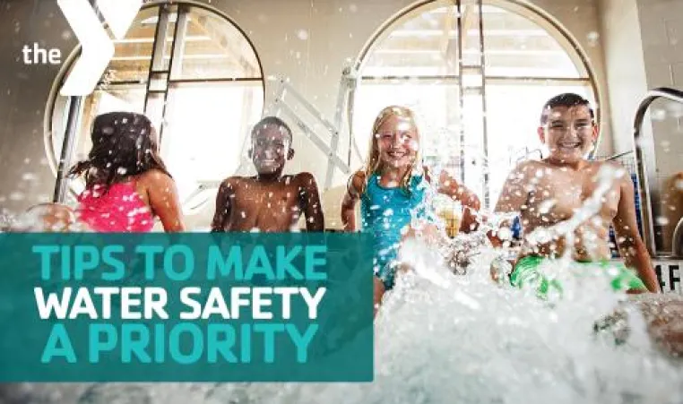 Four kids sitting on the ledge of an indoor pool while kicking their feet to create a splash.