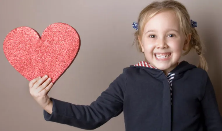 Young girl hold a glittery heart cut out in support of heart health for the Kansas City YMCA