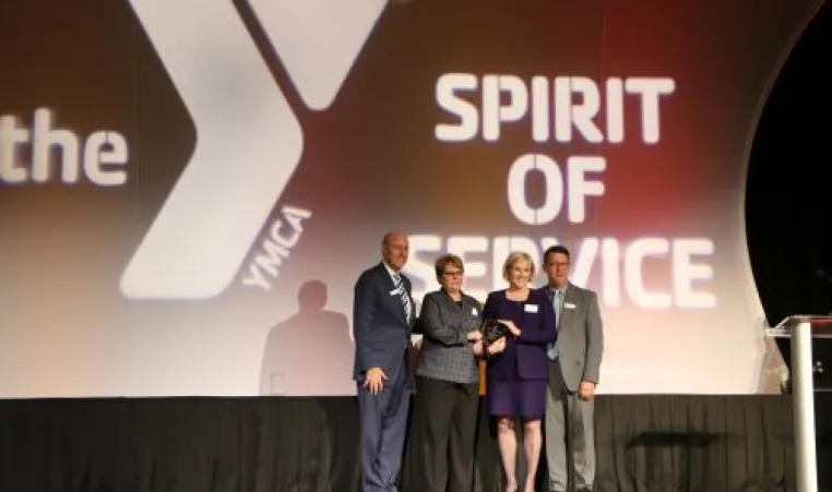 a group of four people standing on the event stage holding an award.