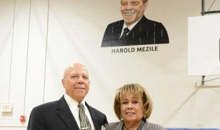 Harold and Peggye Mezile standing in front of his portrait.