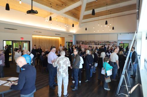 Photo of full room of people at public meeting looking at boards presenting options for Prairie Village Community Center Campus.