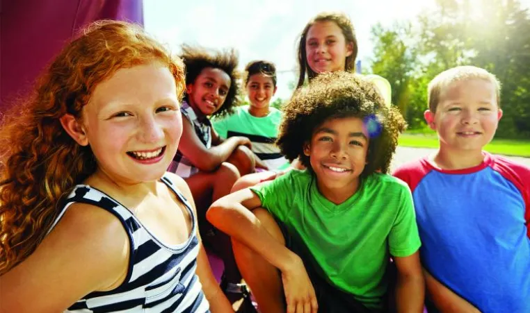 Six kids are gathered together outside smiling at the camera