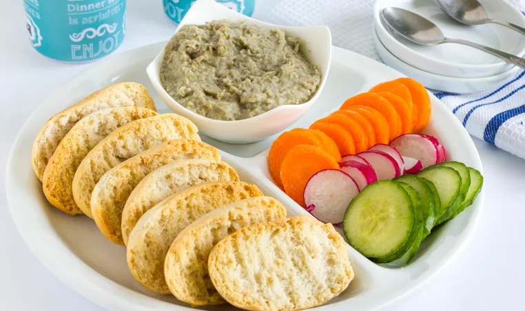 Party platter of healthy snacks including vibrant veggies, whole grain crackers, and hummus.