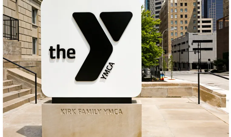 Photo of monument sign outside the Kirk Family YMCA. Include black logo on white background, with Kirk Family YMCA engraved on stone base.