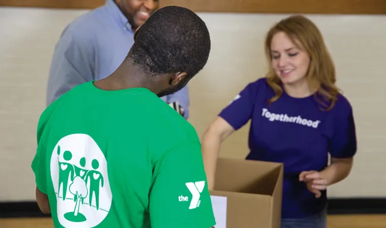 3 volunteers working the Volunteer book drive. 2 of the volunteers are wearing Greater Kansas City YMCA volunteer t-shirts.