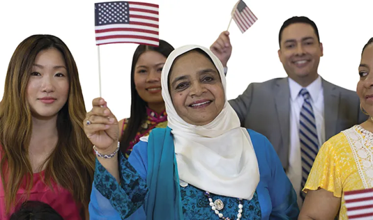 Group of people smiling while waving small American flags at naturalization ceremony.