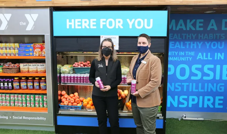 Shari Coulter Ford, Tohi Beverages, and Tina Weaver, North Kansas City YMCA Executive Director, hold cans of Tohi Beverages at the Marketplace Food Pantry at North Kansas City YMCA.