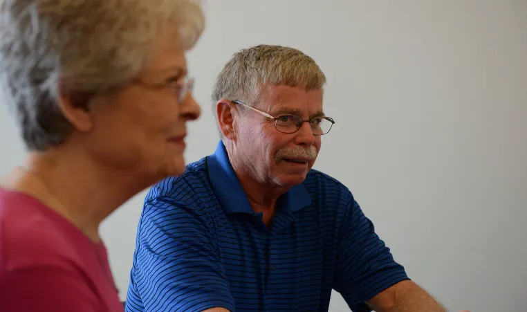 Older gentleman and woman drinking coffee while conversing.