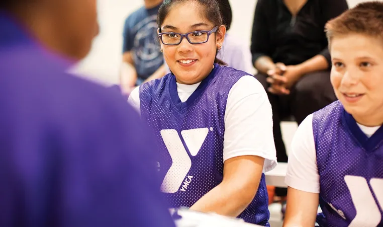 Two teen YMCA members talking with a YMCA coach.