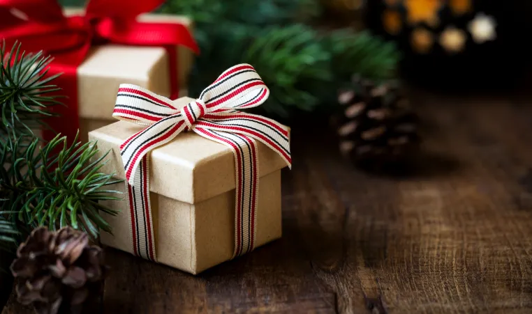 Wrapped gifts surrounded by pine tree branches on a wooden table.