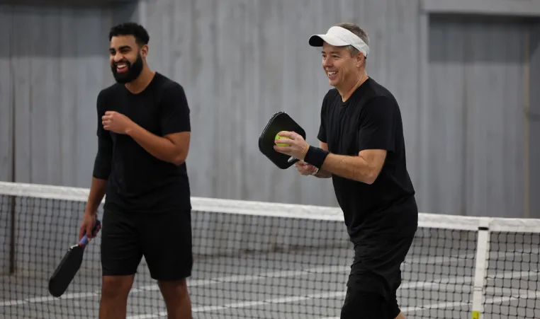 Picture of two men playing pickleball and smiling