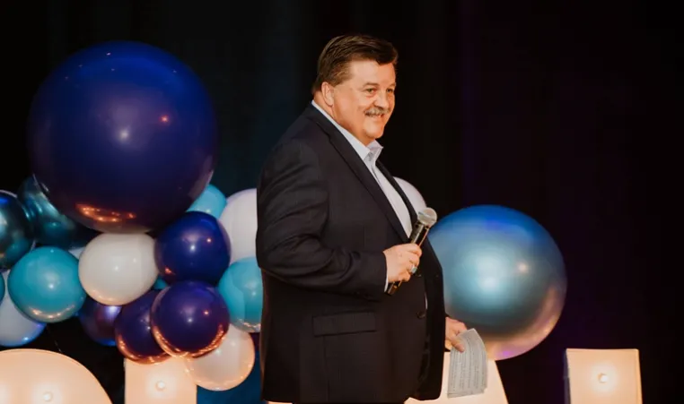 Greg Westbrook speaks on stage at a past Challenge Your Fashion fundraiser for the YMCA Challenger Program