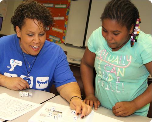 Photo of a Y Club leader using dice to play a learning game with a student