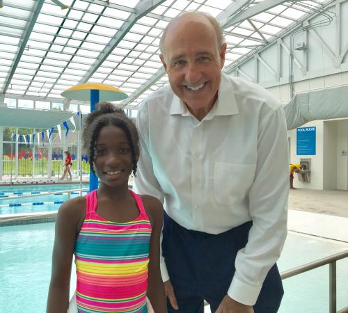 Taliya, swim lesson participant, and David Byrd, President and CEO, standing next to the pool at the Linwood YMCA.