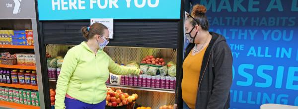 A woman picks up a can of Tohi wellness beverage at the North Kansas City YMCA Marketplace Food Pantry