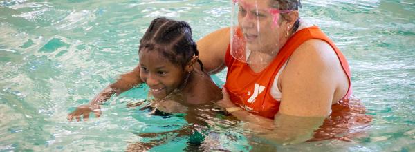 Y swim instructor holds student in water to help him practice swim skills
