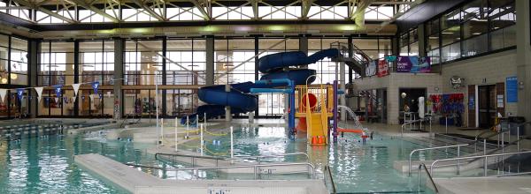 A wide shot looking at swimming area, large slide and kiddie playground at North Kansas City YMCA pool